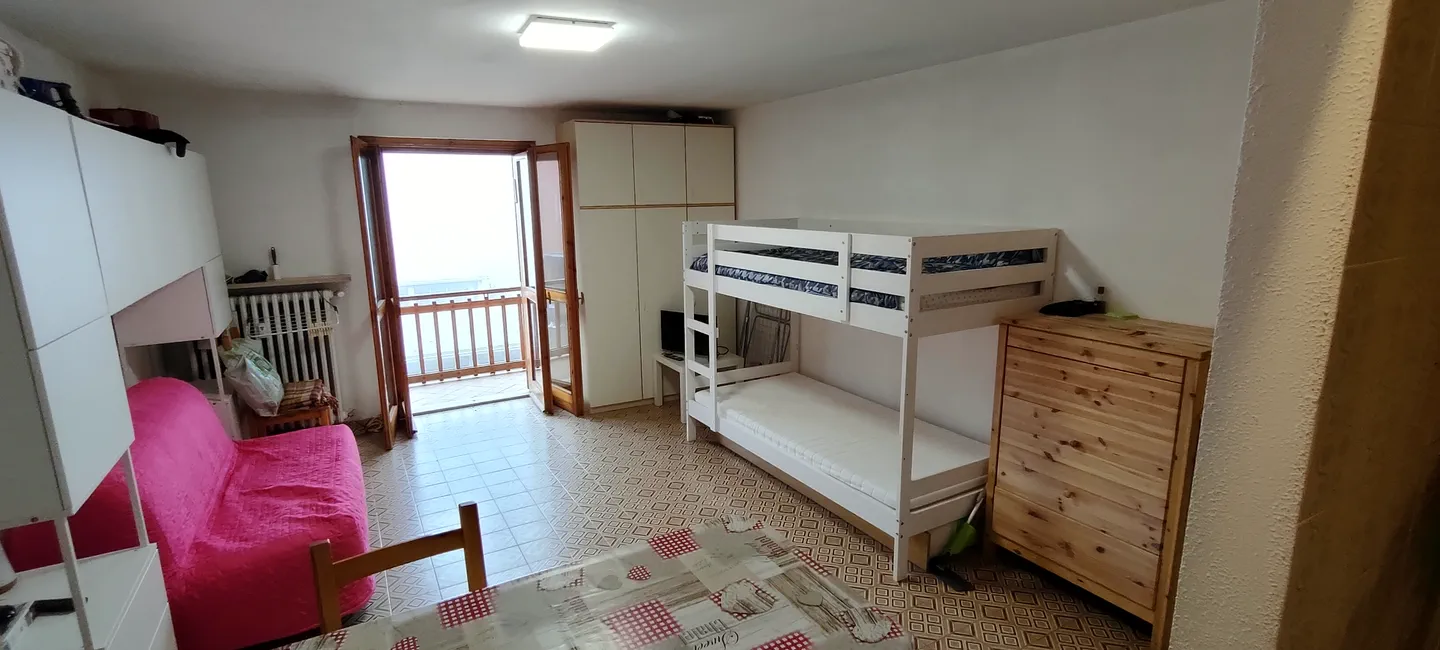 Il soggiorno dell'appartamento a Prato Nevoso con letto a castello, divano e portafinestra aperta sul balcone
