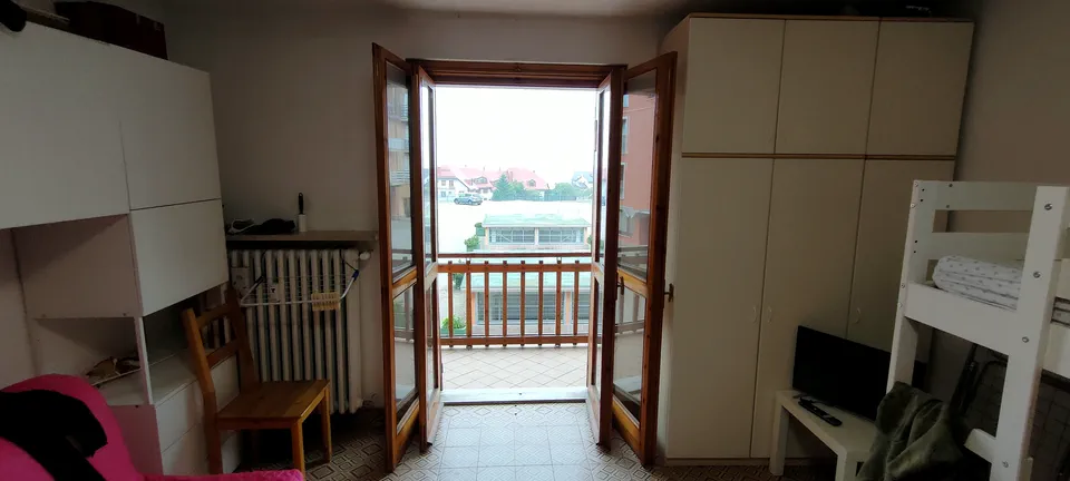 Portafinestra aperta sul balcone dell'appartamento con letto a castello accanto
